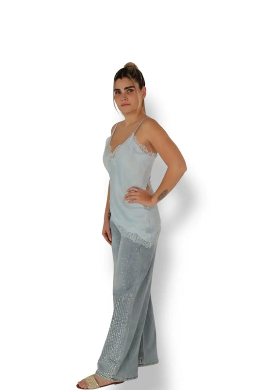 Mujer con blusa de tirantes azul claro y pantalón de mezclilla con pedrería, fondo blanco