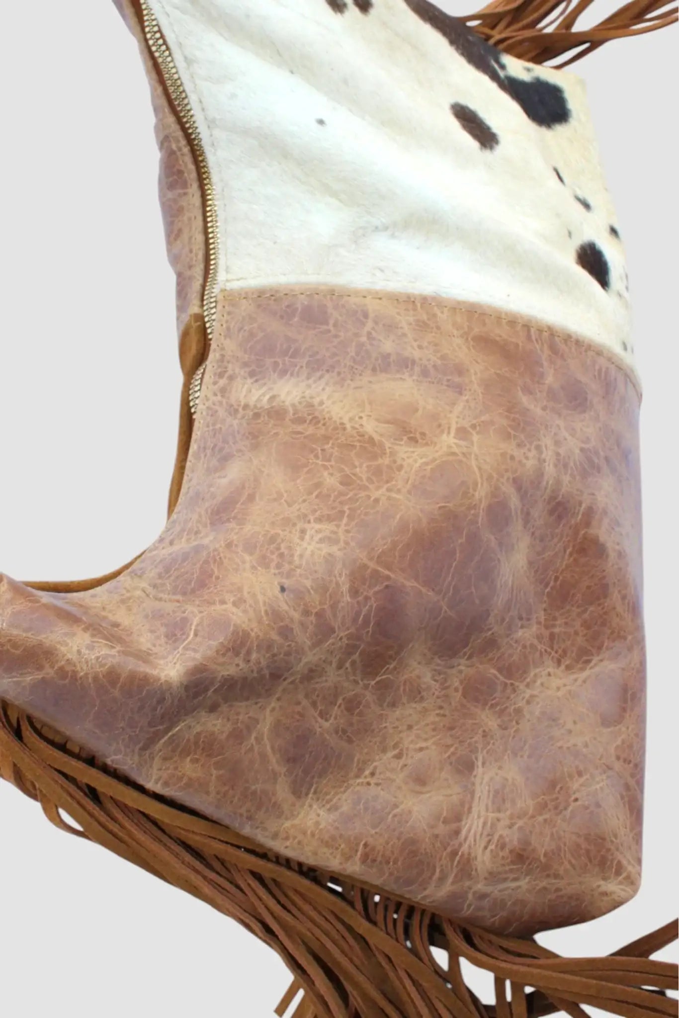 Bolso de cuero y piel sintética con flecos, diseño vaquero y cremallera dorada.