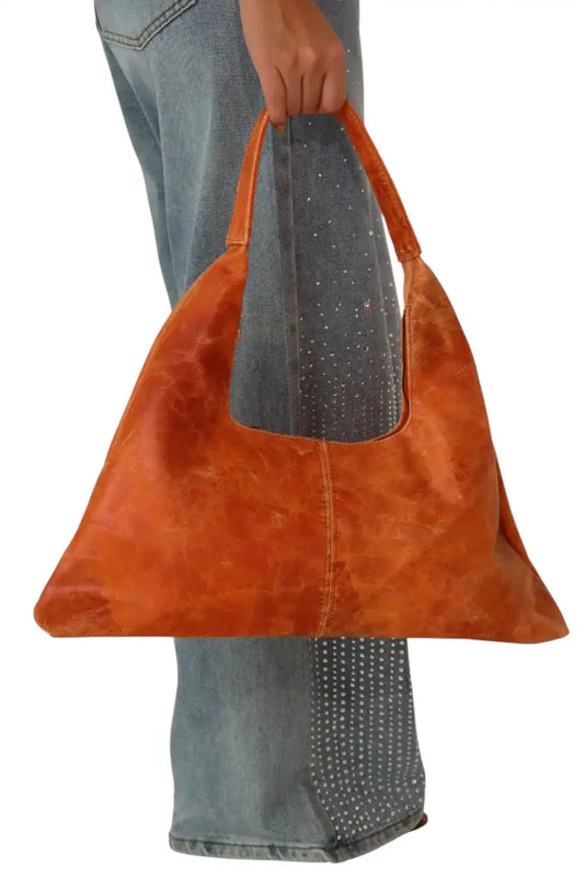 Bolso de mano grande marrón de cuero estilo minimalista, con pantalón de mezclilla