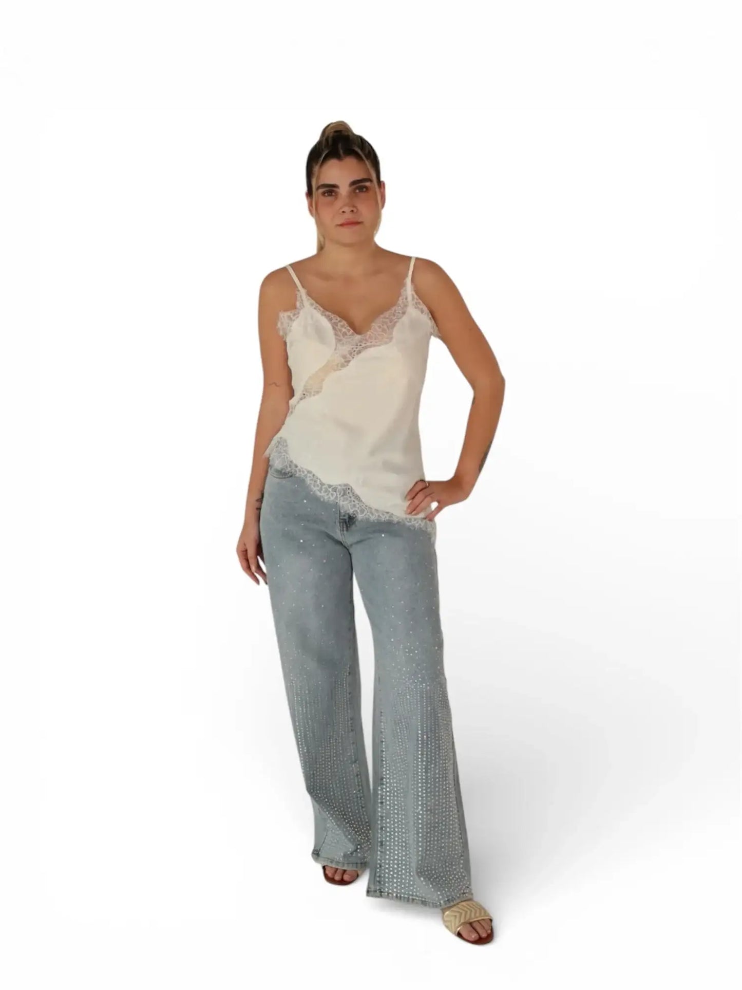 Mujer con blusa de tirantes blanca y encaje, jeans azul claro con pedrería y sandalias beige