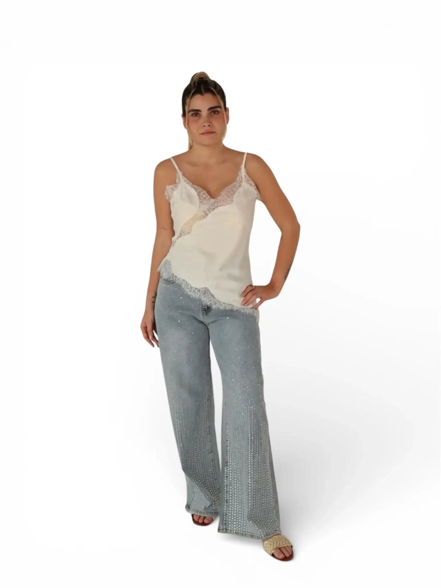 Mujer con blusa de tirantes blanca y encaje, jeans azul claro con pedrería y sandalias beige