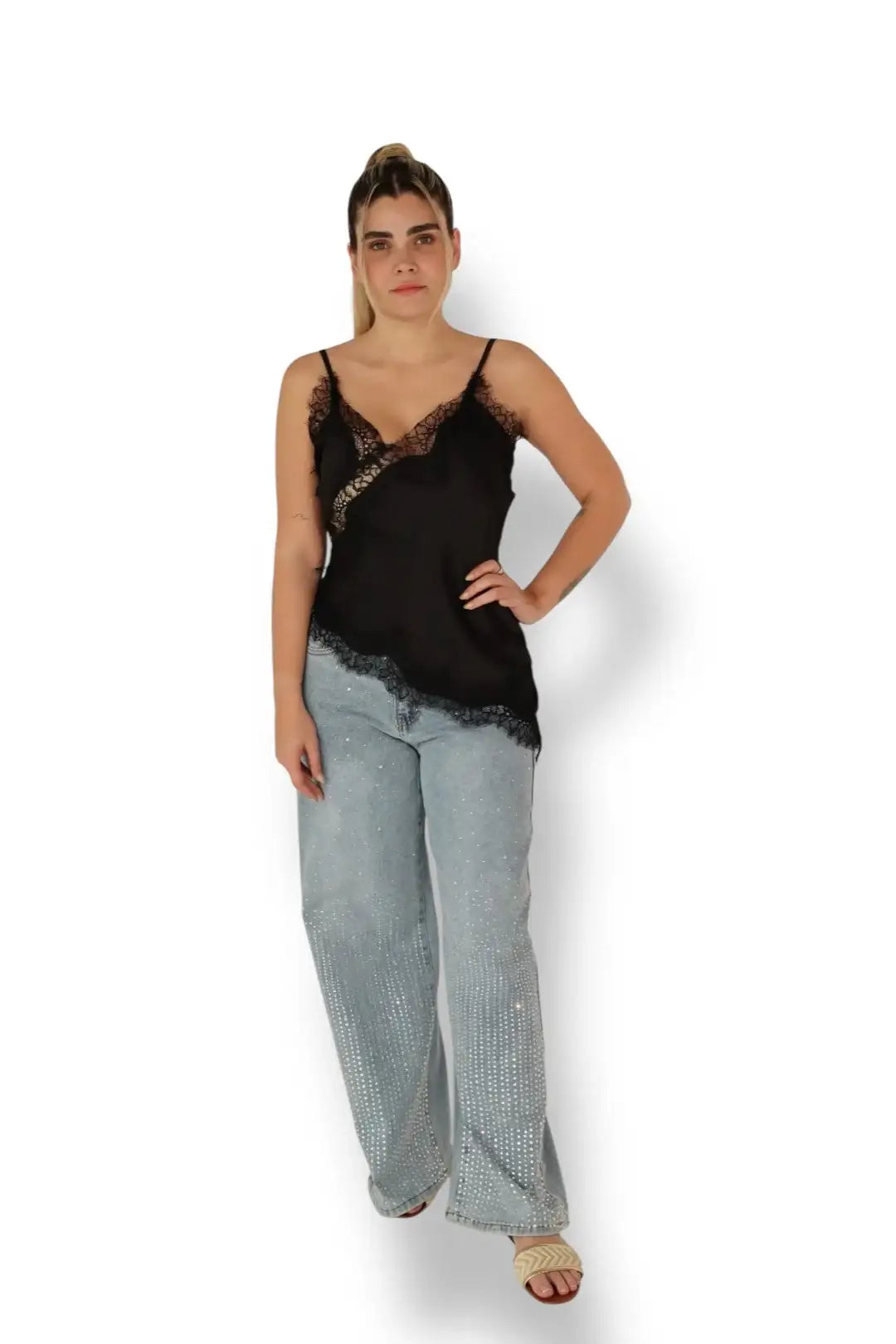 Mujer con blusa de tirantes negra con encaje y pantalón de mezclilla claro con perlas