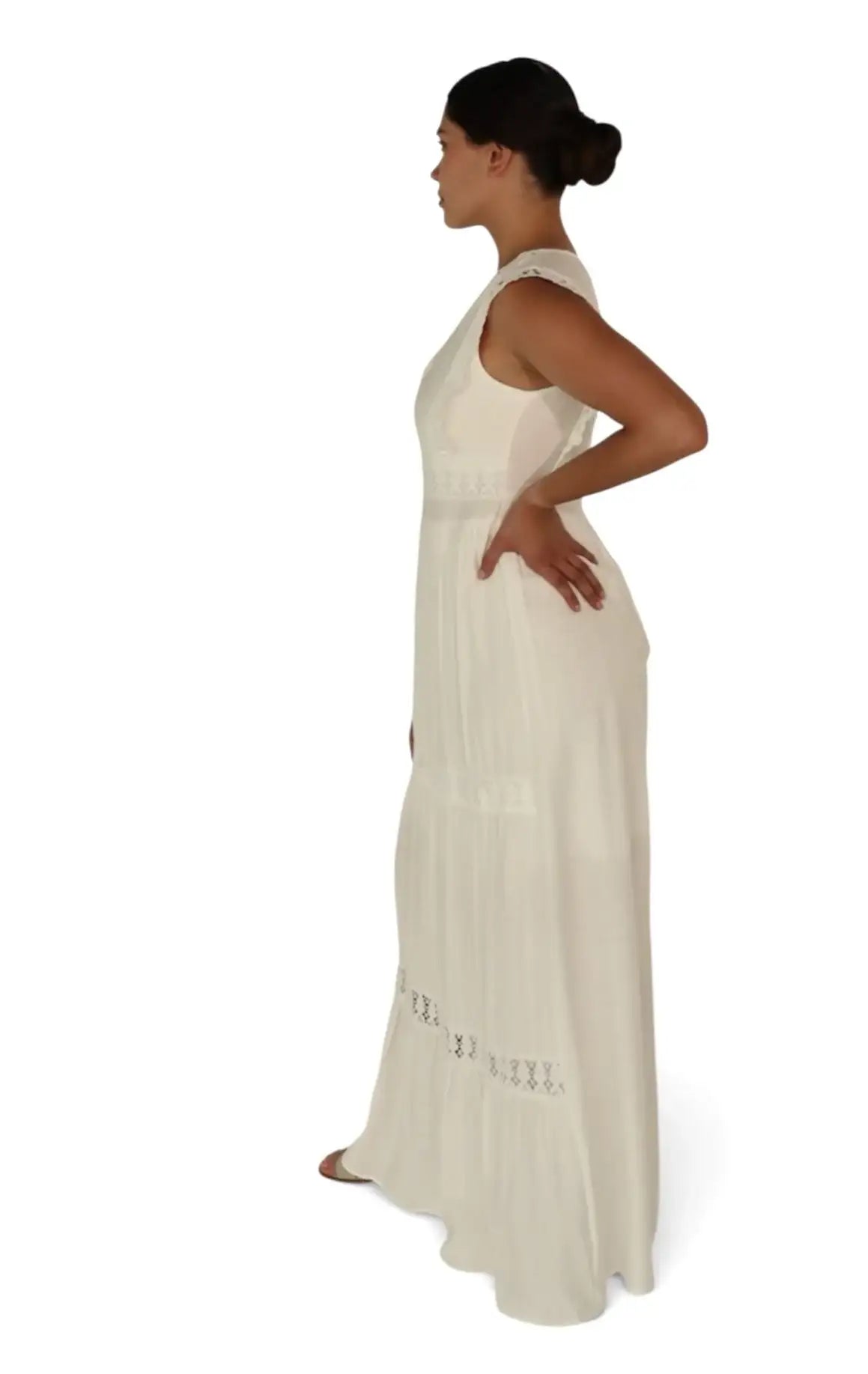 Mujer de perfil con vestido largo blanco de tirantes y detalles bordados, fondo blanco