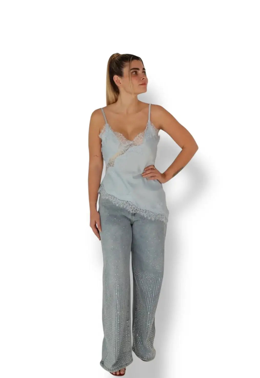 Mujer con blusa de tirantes celeste y encaje, pantalón ancho de mezclilla con brillos