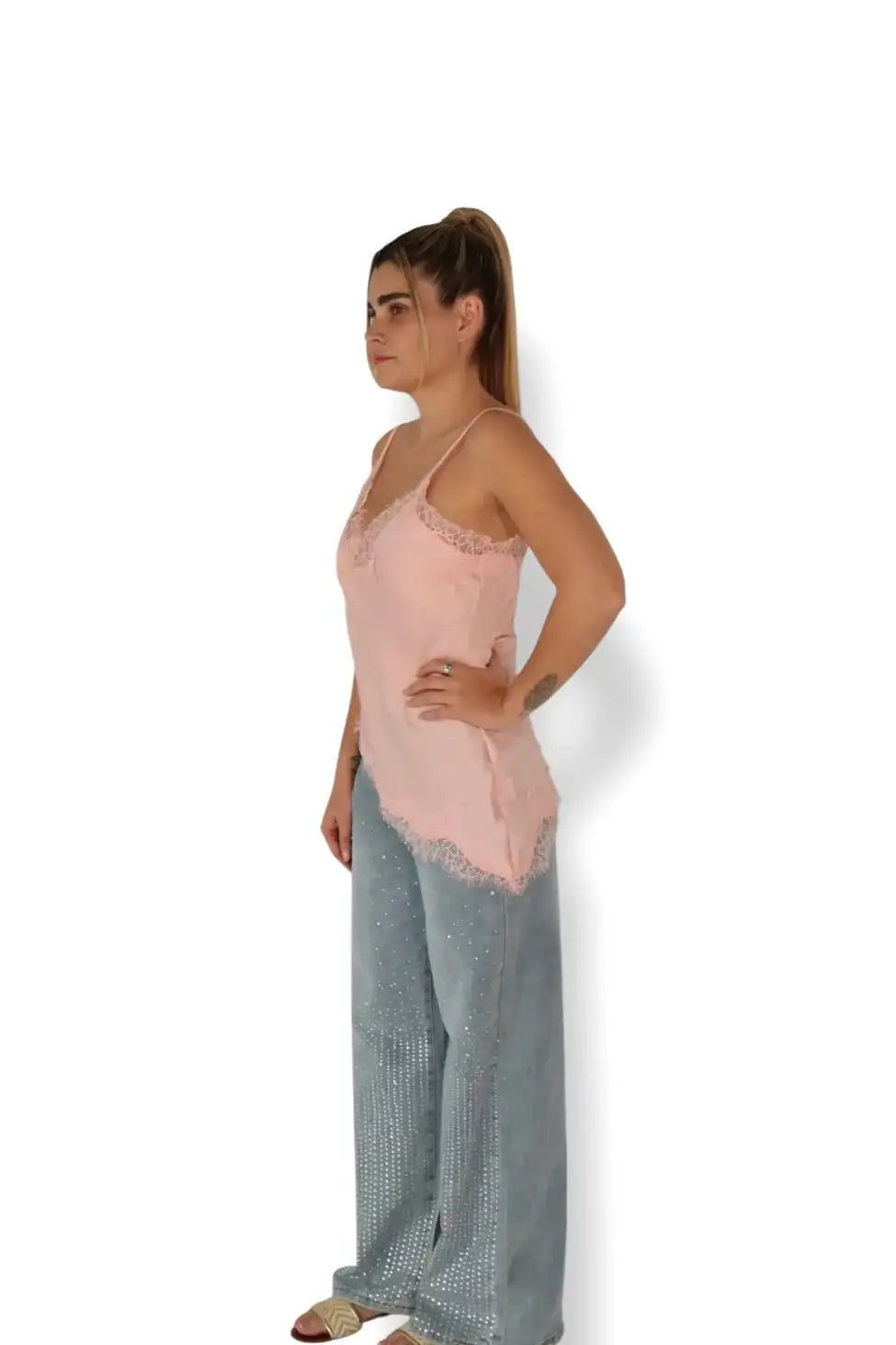 Mujer con blusa rosa de encaje y pantalón de mezclilla ancho con pedrería, moda casual