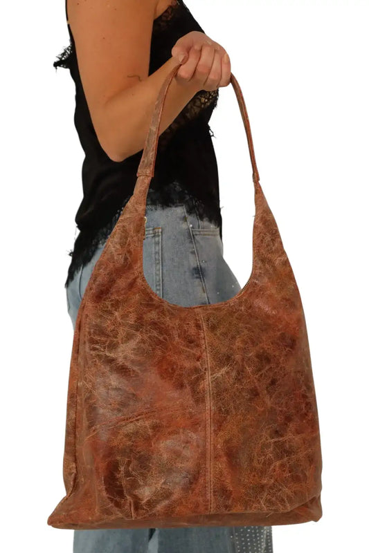 Bolso grande de hombro café estilo vintage, mujer con top negro y jeans claros