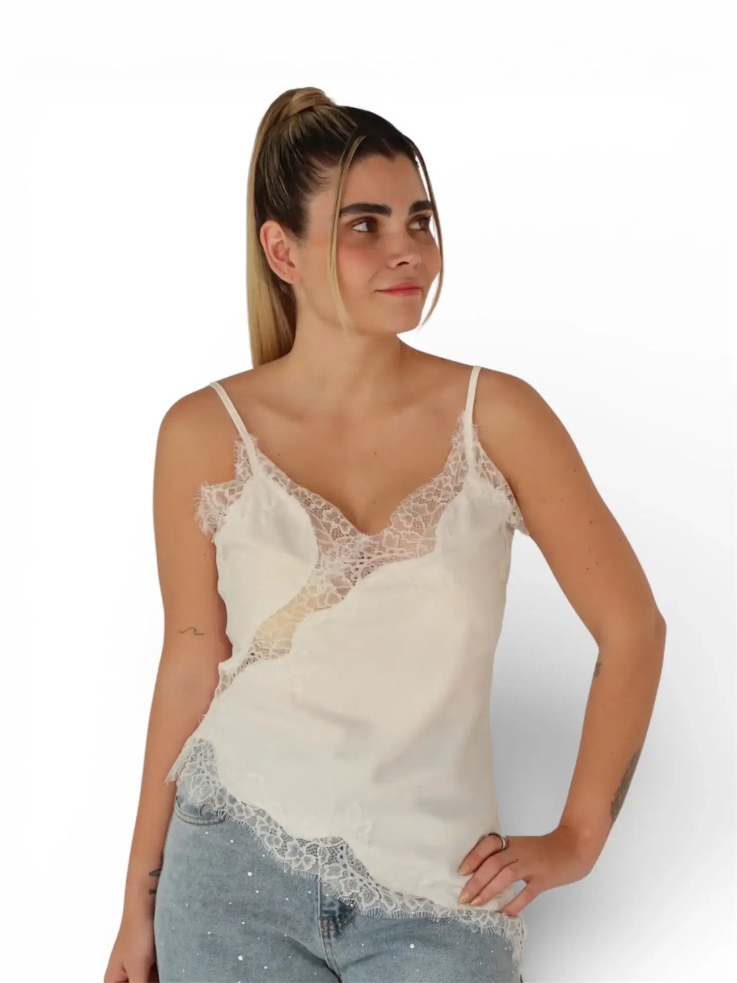 Mujer con blusa de encaje blanca y tirantes, combinada con jeans, fondo blanco.