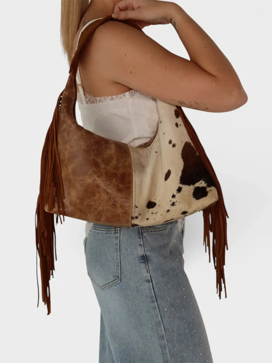 Bolsa de hombro de piel con estampado tipo vaca y flecos, outfit casual mujer.