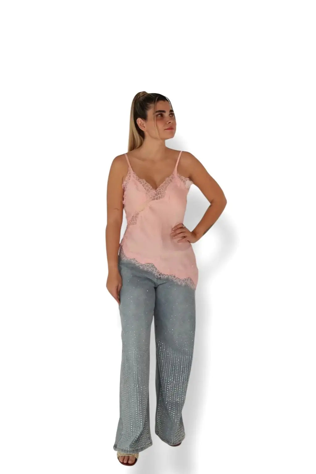 Mujer con blusa rosa de encaje y pantalón de mezclilla azul con pedrería, moda juvenil elegante