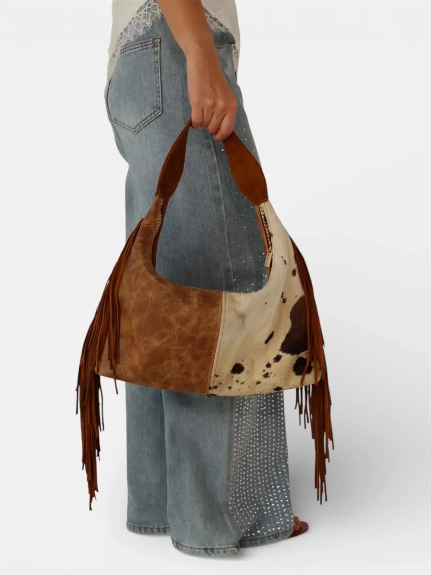 Bolso de cuero con flecos tipo hobo, estampado de vaca, combinado con jeans acampanados