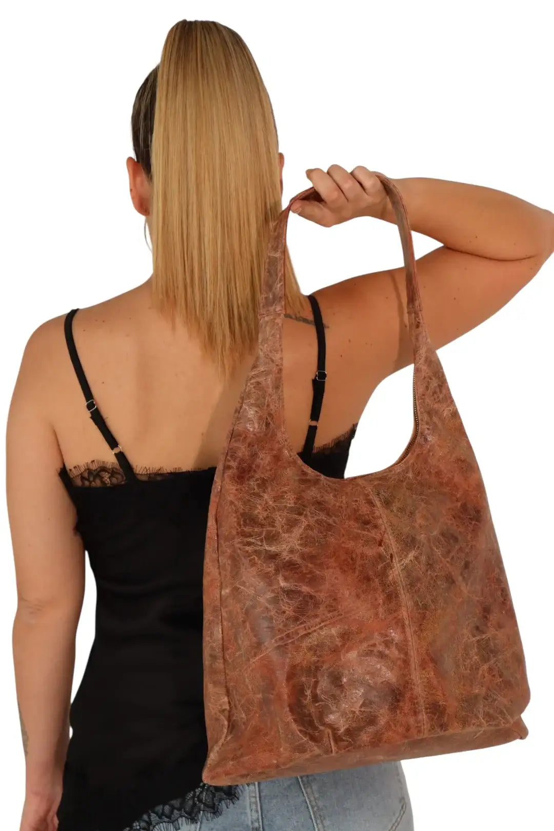 Mujer con bolso grande de piel marrón, look casual, blusa negra y jean, fondo blanco