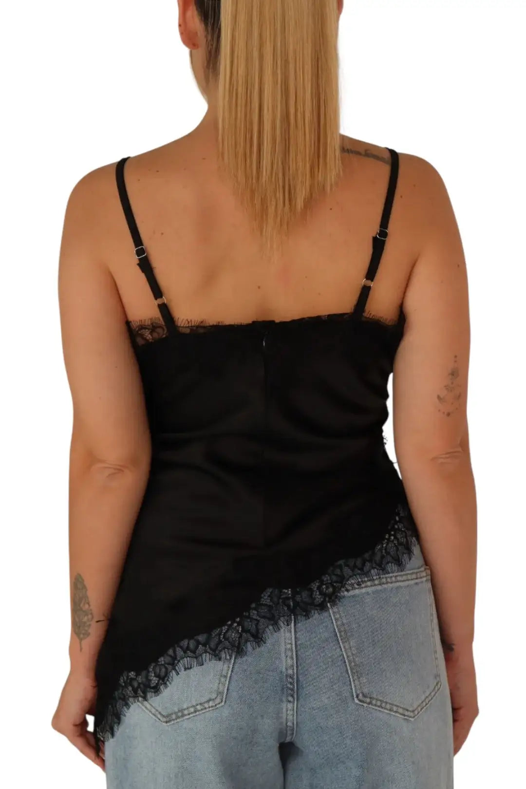 Mujer de espaldas con blusa negra de tirantes y encaje y jeans claros estilo casual