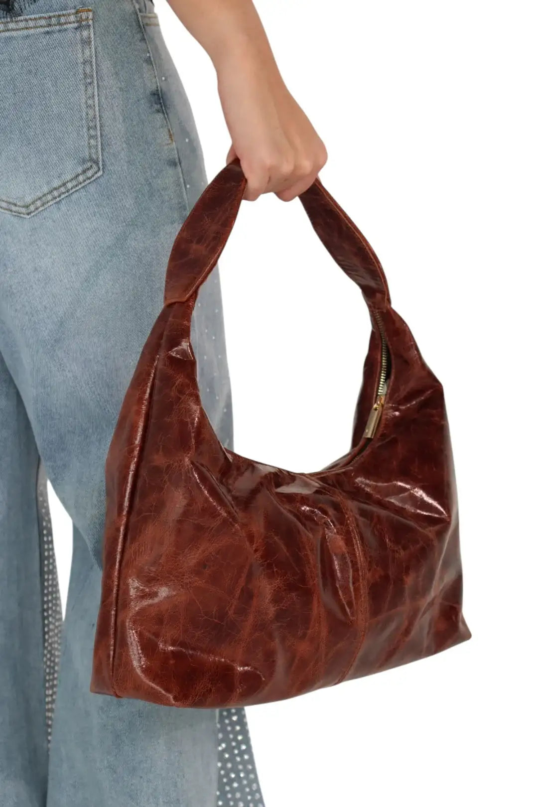 Bolsa de hombro café de cuero, textura arrugada, combinada con jeans claros