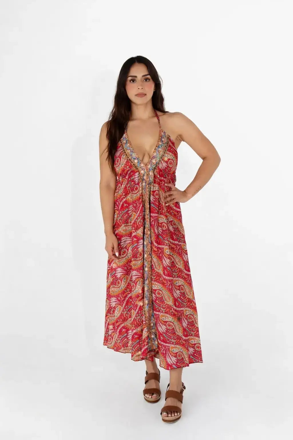 Mujer con vestido largo estampado rojo con escote halter, sandalias marrón, fondo blanco