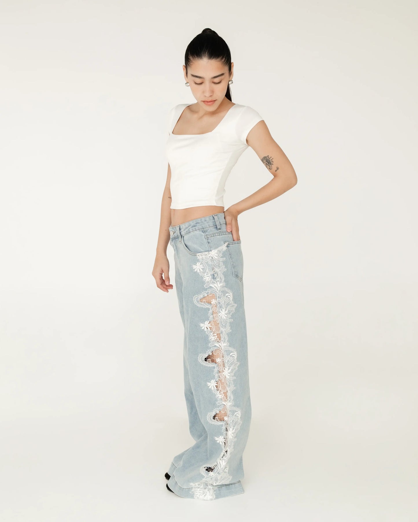 Mujer luciendo pantalón de mezclilla azul claro con encaje blanco y top blanco corto