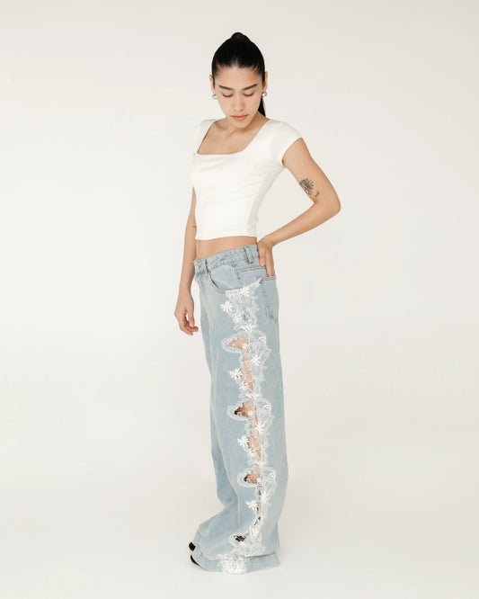 Mujer luciendo pantalón de mezclilla azul claro con encaje blanco y top blanco corto