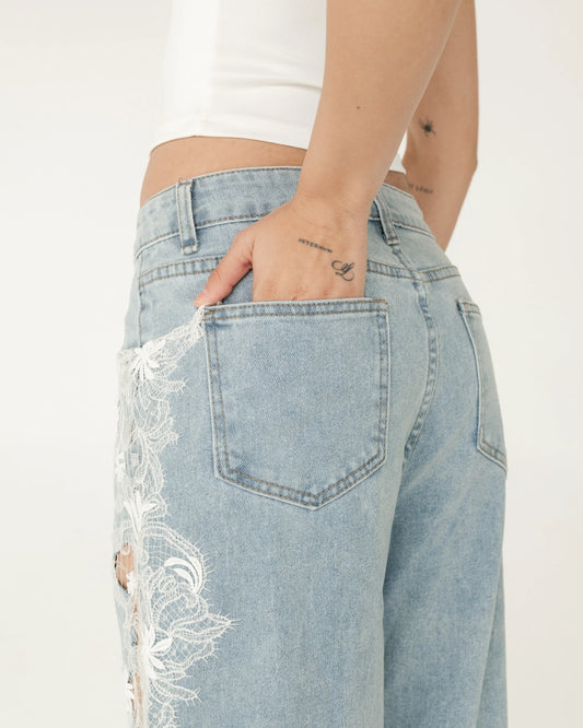 Jeans de mezclilla azul claro con encaje blanco en costado, modelo de mujer