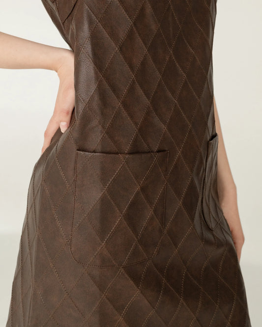 Vestido de cuero café acolchonado con bolsillos y costuras en rombo, vista lateral.