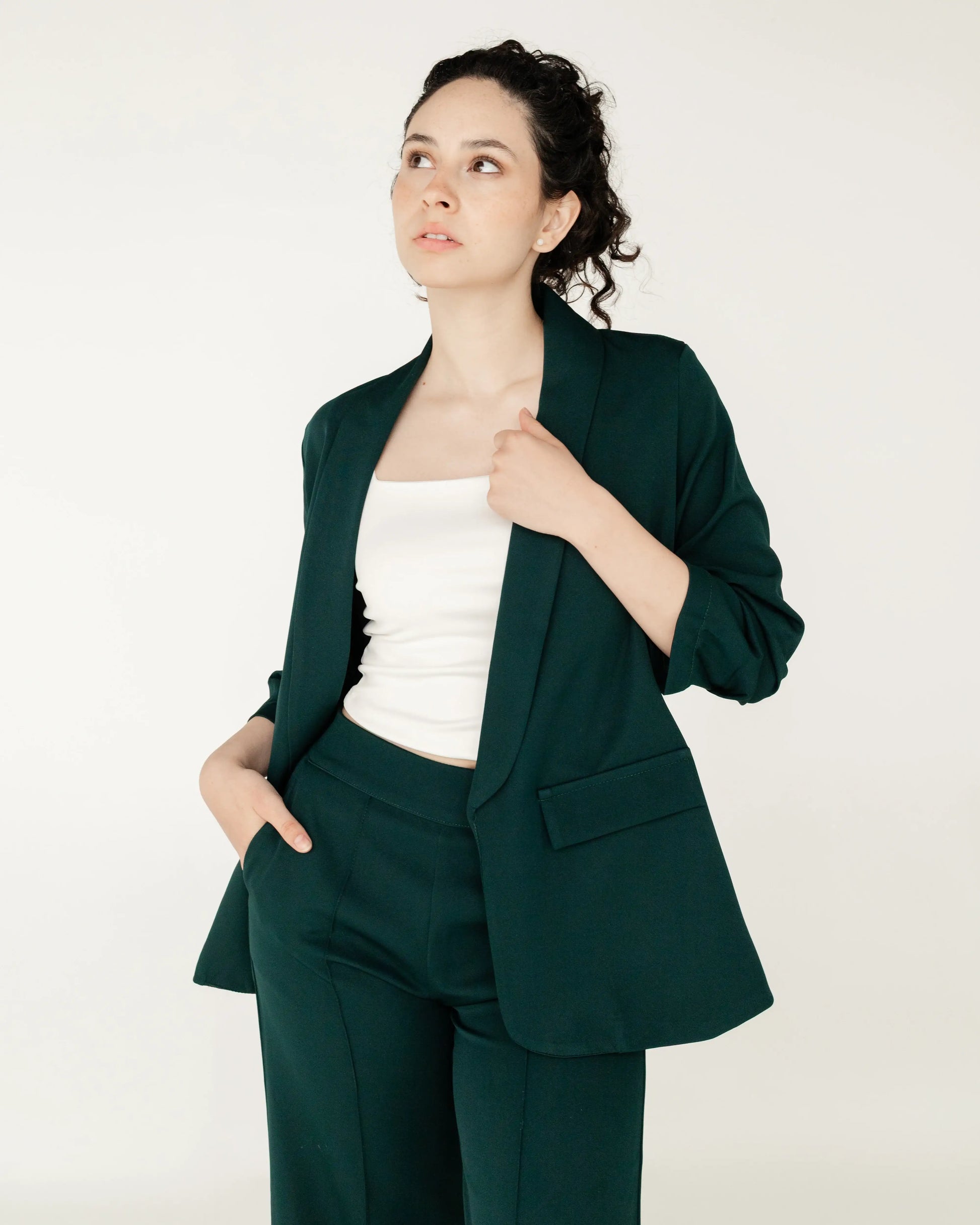 Mujer con blazer y pantalón verde oscuro, look formal moderno, fondo claro