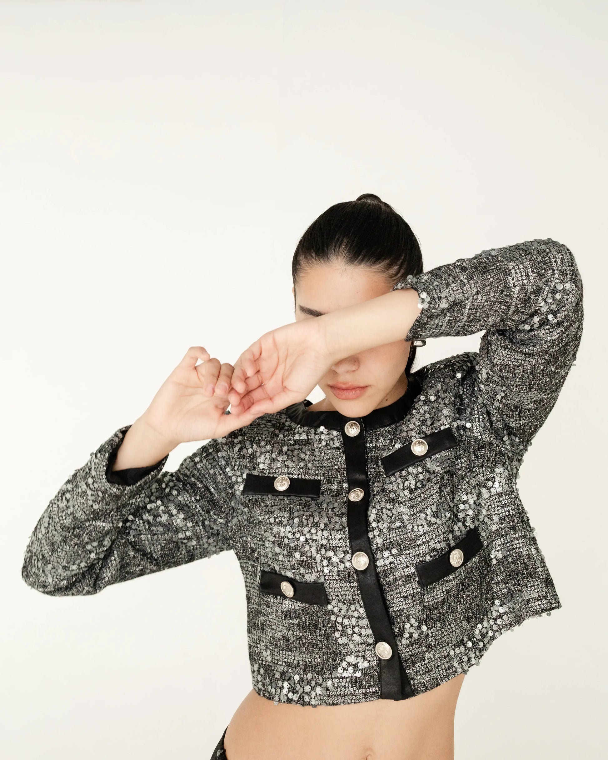 Mujer con chaqueta corta de lentejuelas gris y detalles negros, moda elegante