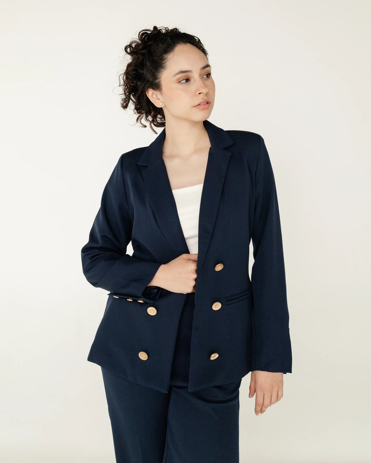 Mujer con blazer azul marino y botones dorados, look formal y moderno