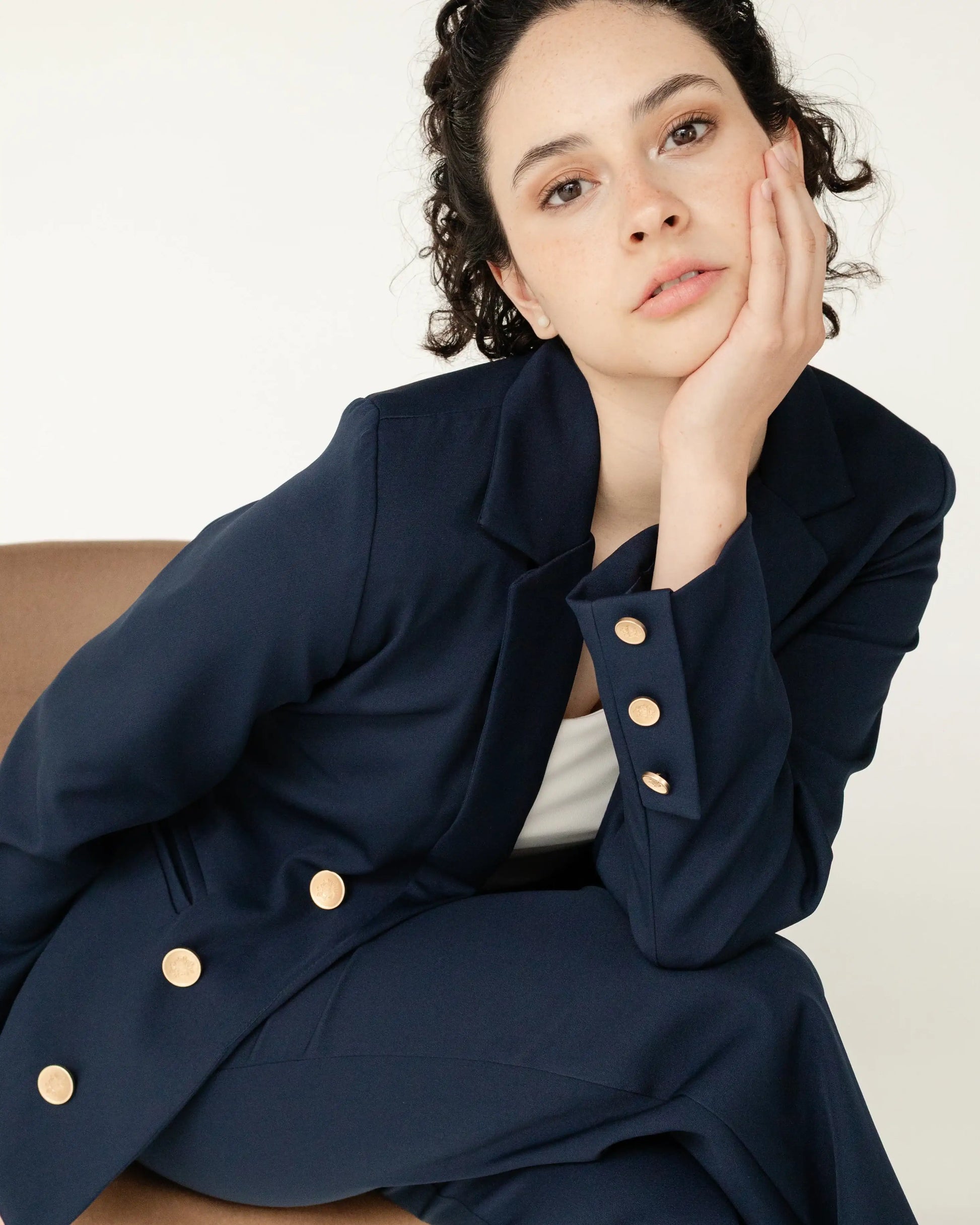 Mujer joven con saco azul marino elegante y botones dorados, moda moderna latinoamericana