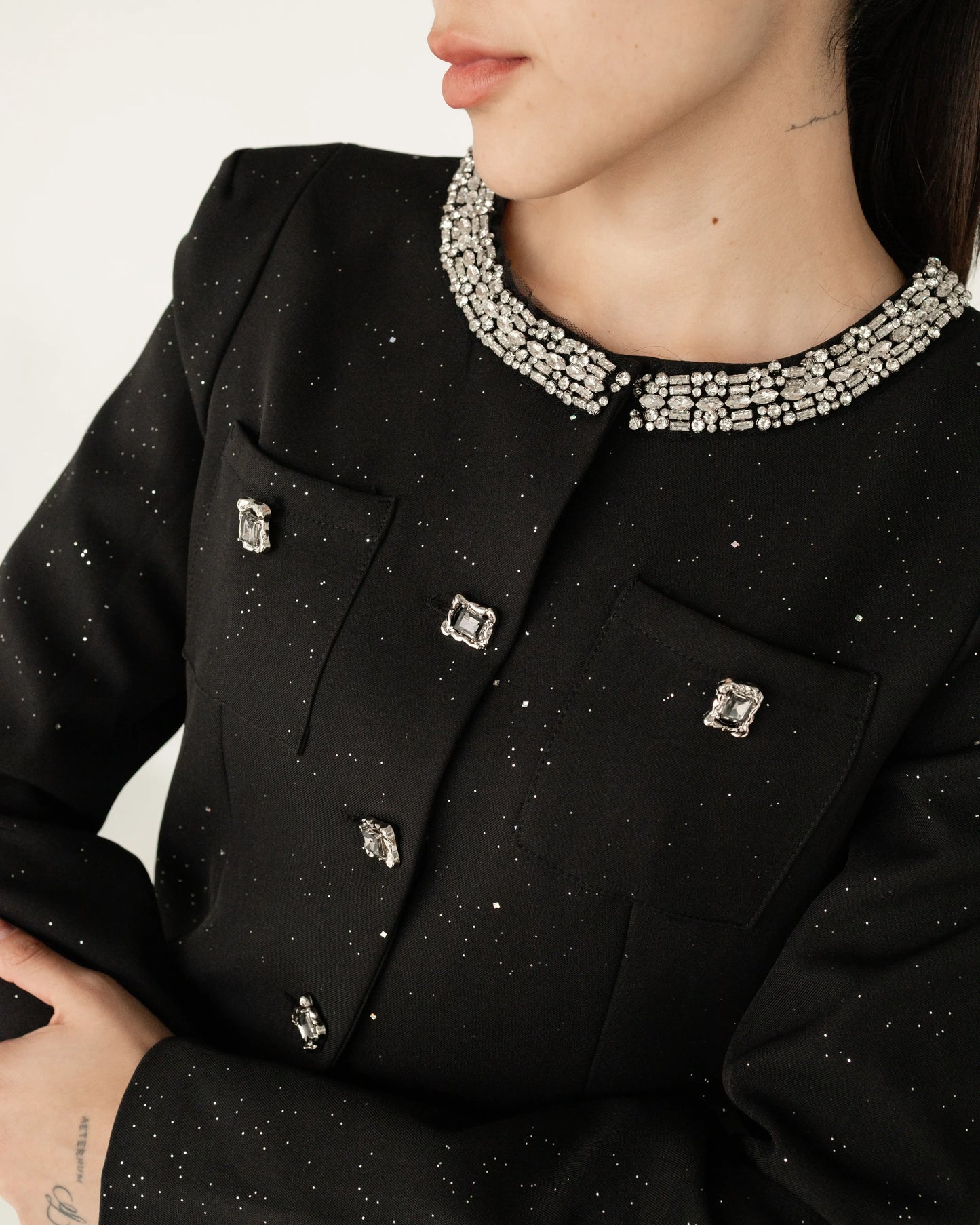 Saco negro elegante para mujer con botones y cuello con pedrería, detalles brillantes