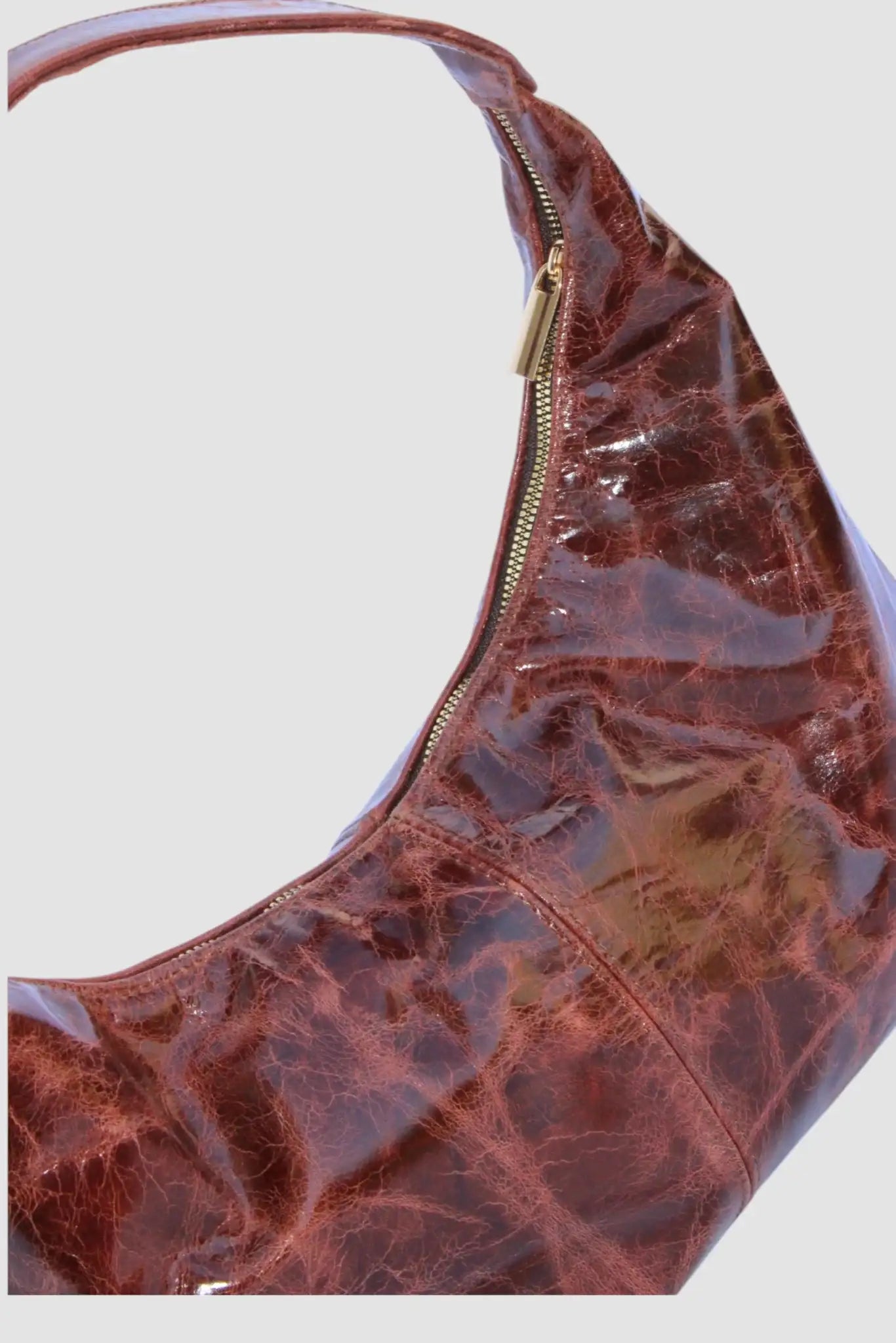 Bolso de hombro marrón de vinil con textura brillante y cierre dorado, estilo moderno