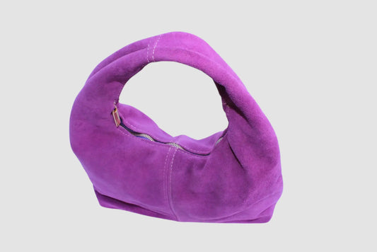 Bolsa de mano morada de gamuza con asa ancha y cierre, fondo blanco