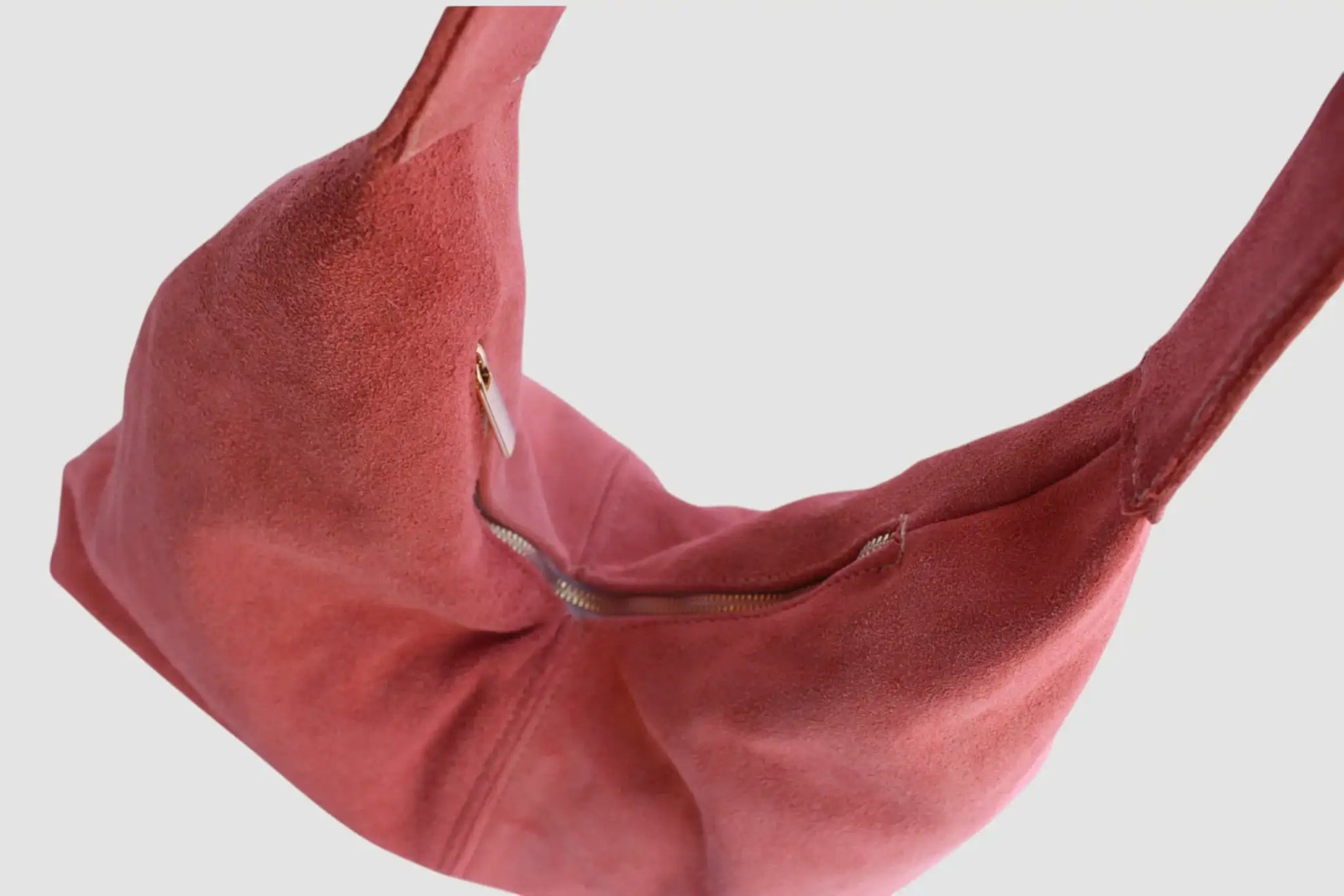Bolsa tipo hobo de gamuza rosa con cierre dorado, vista superior sobre fondo claro