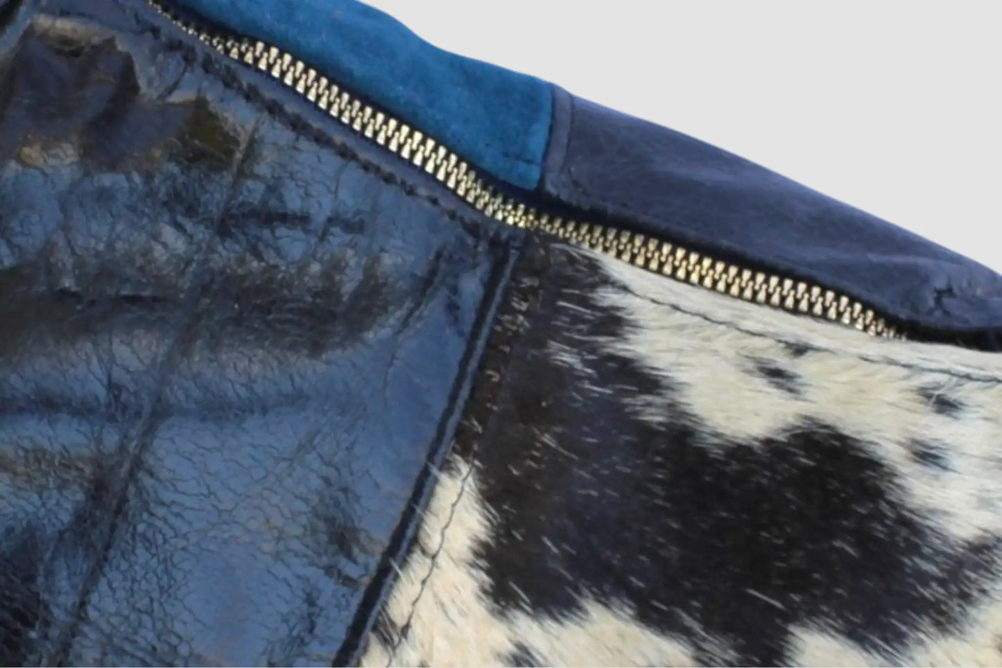 Detalle de bolso de piel azul y estampado animal con cierre metálico dorado