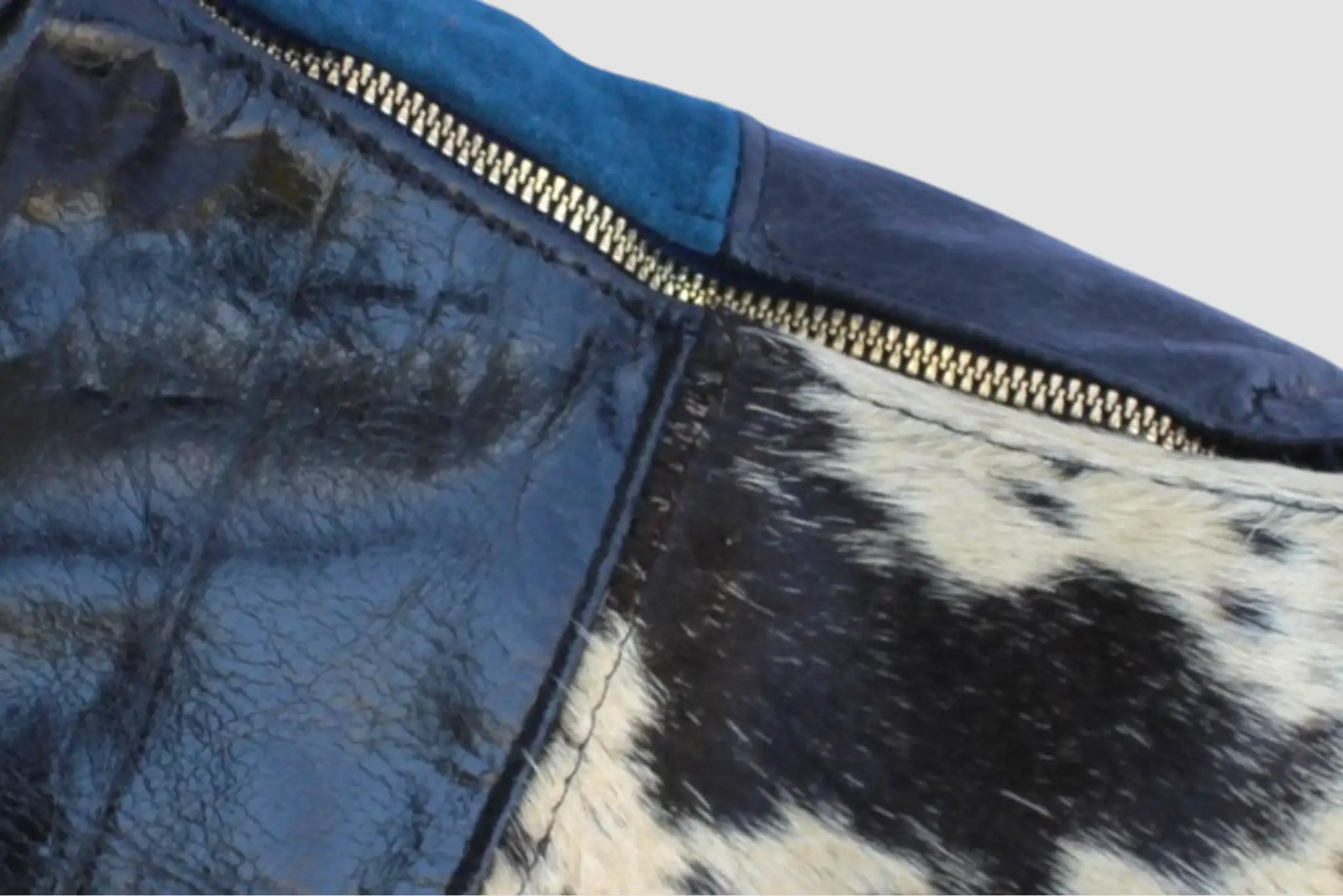 Detalle de bolso de piel azul y estampado animal con cierre metálico dorado